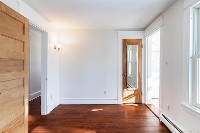 unfurnished room featuring dark wood-type flooring and a baseboard heating unit