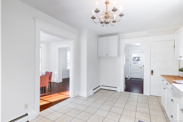 kitchen featuring white cabinetry, a baseboard radiator, a healthy amount of sunlight, and light tile patterned floors