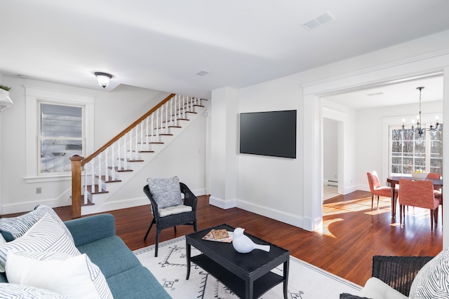 living room featuring hardwood / wood-style flooring, a baseboard heating unit, and a notable chandelier