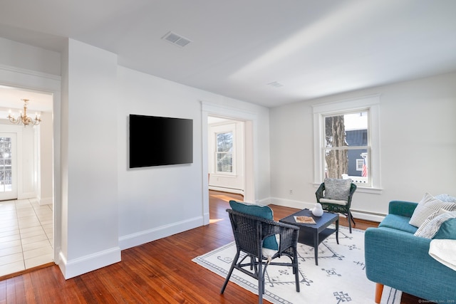 living room featuring an inviting chandelier, hardwood / wood-style floors, and baseboard heating