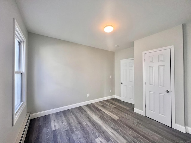 unfurnished bedroom featuring a baseboard radiator and dark hardwood / wood-style floors