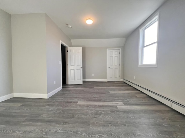 unfurnished bedroom featuring a baseboard radiator, dark hardwood / wood-style floors, and lofted ceiling