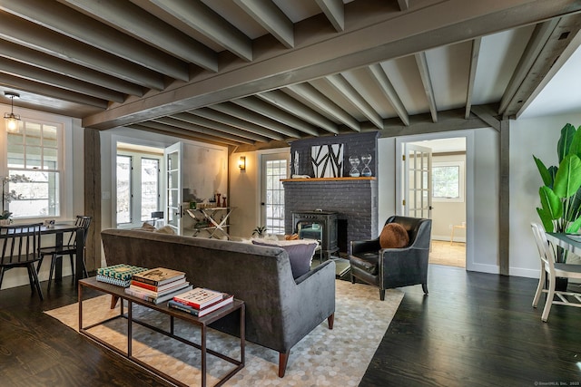 living room with beamed ceiling, plenty of natural light, hardwood / wood-style floors, and a brick fireplace