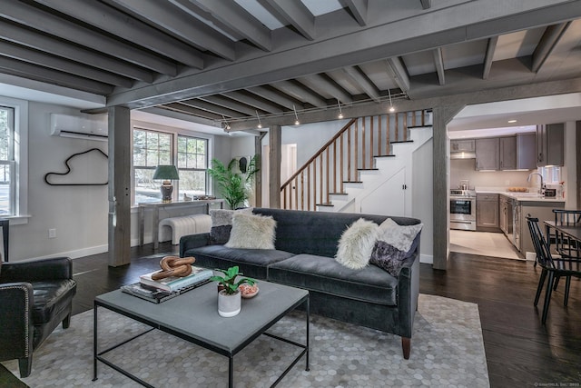 living room with sink, track lighting, dark hardwood / wood-style floors, a wall unit AC, and beam ceiling