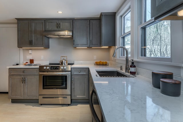 kitchen with stainless steel electric range oven, light stone countertops, and sink