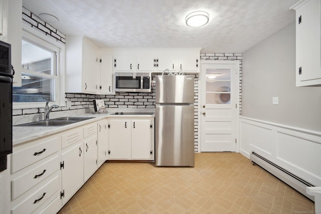 kitchen featuring sink, white cabinetry, a textured ceiling, baseboard heating, and appliances with stainless steel finishes