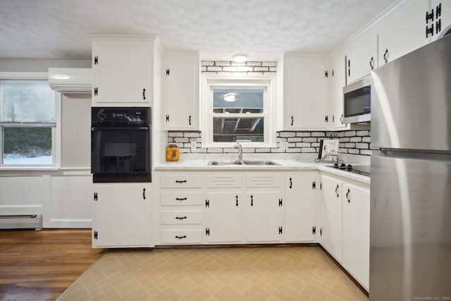 kitchen featuring sink, a baseboard heating unit, a wall unit AC, black appliances, and white cabinets