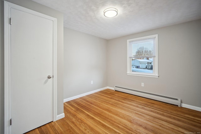 unfurnished room with light wood-type flooring, a textured ceiling, and baseboard heating