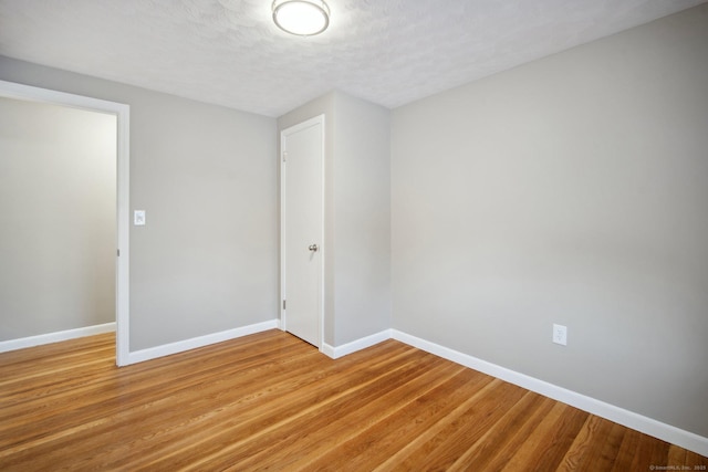 spare room featuring light hardwood / wood-style floors and a textured ceiling