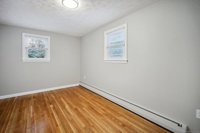 empty room with a baseboard heating unit, wood-type flooring, and a textured ceiling