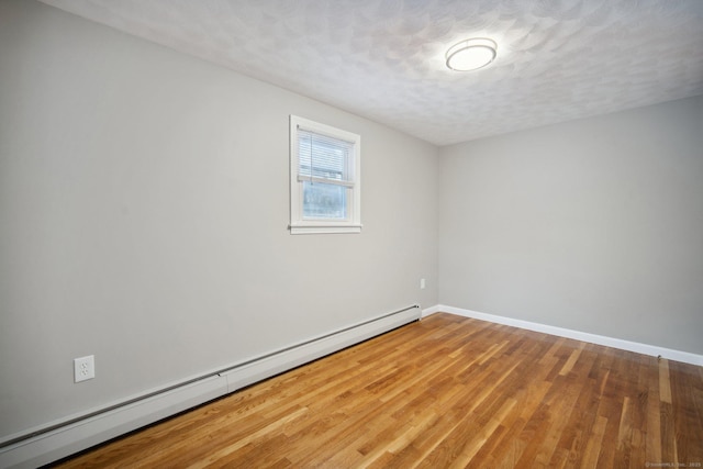 empty room with hardwood / wood-style floors, a textured ceiling, and baseboard heating