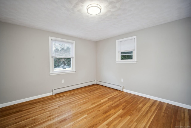 unfurnished room with light hardwood / wood-style flooring and a baseboard heating unit