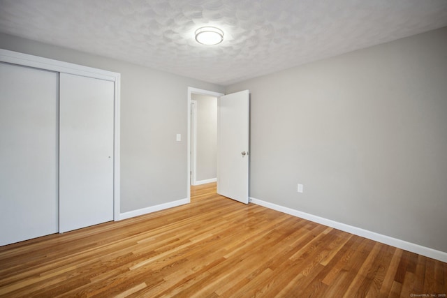 unfurnished bedroom with light hardwood / wood-style flooring, a textured ceiling, and a closet