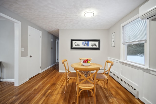 dining space with a baseboard heating unit, dark wood-type flooring, a textured ceiling, and a wall unit AC