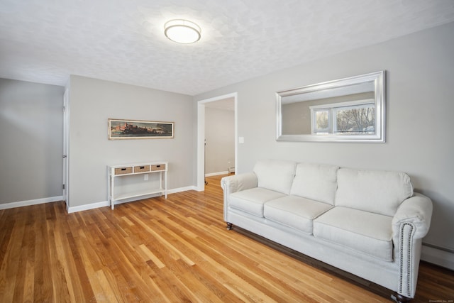 living room featuring wood-type flooring, a textured ceiling, and baseboard heating