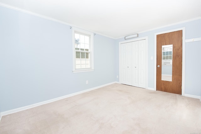 unfurnished bedroom featuring light carpet, ornamental molding, and a closet