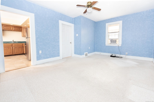 carpeted spare room featuring sink and ceiling fan