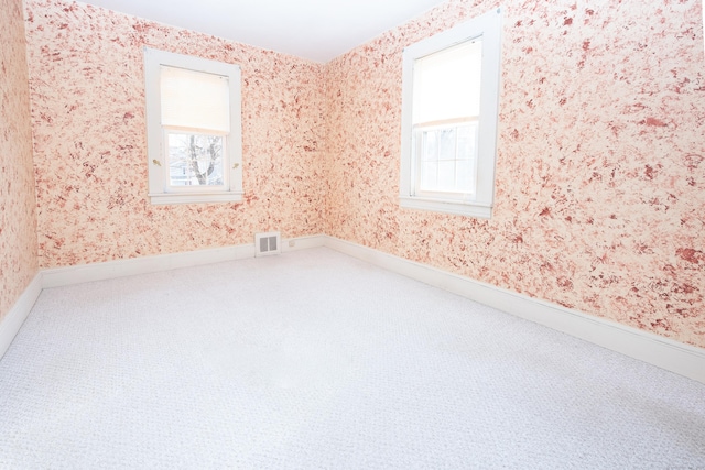 empty room with plenty of natural light and carpet floors