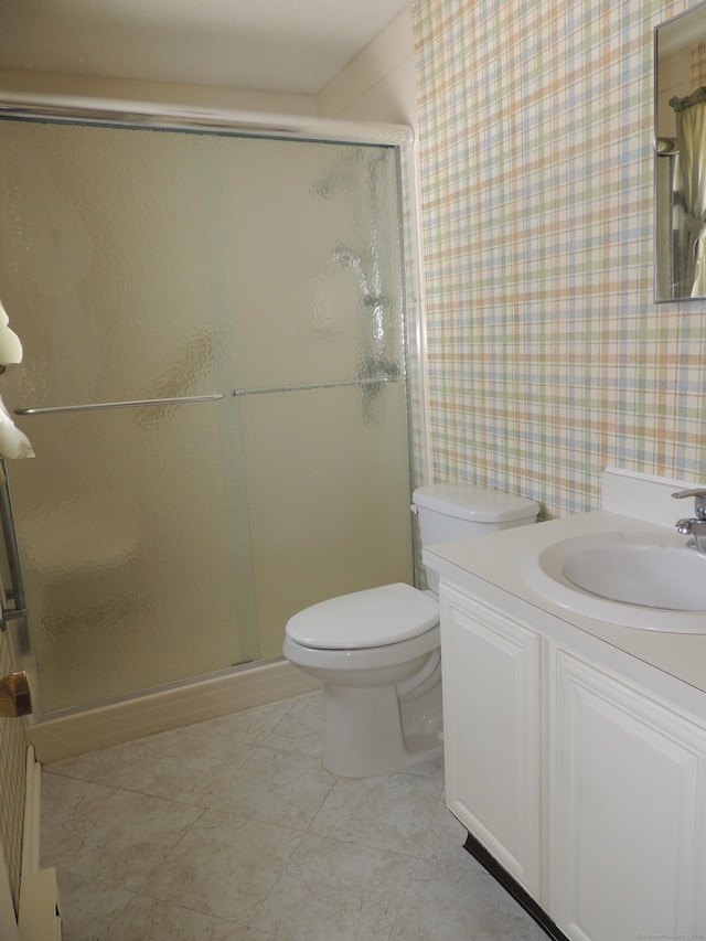 bathroom featuring tile patterned floors, vanity, toilet, and a shower with door