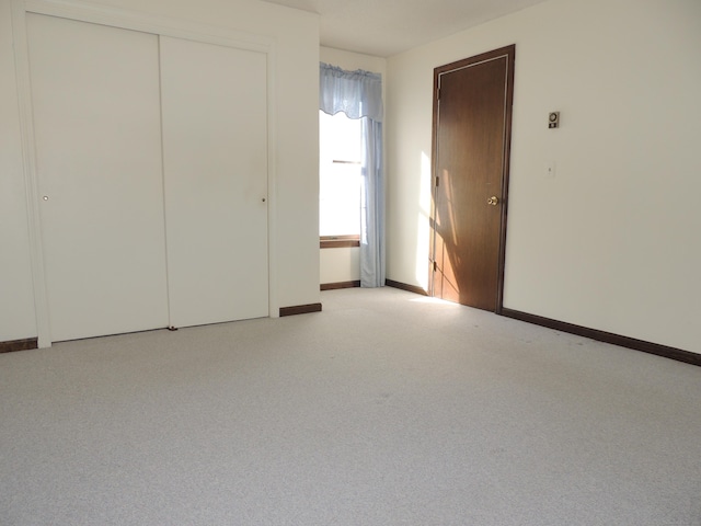 unfurnished bedroom featuring light carpet and a closet