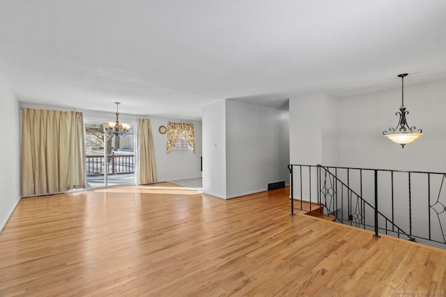 spare room featuring a notable chandelier and light hardwood / wood-style floors