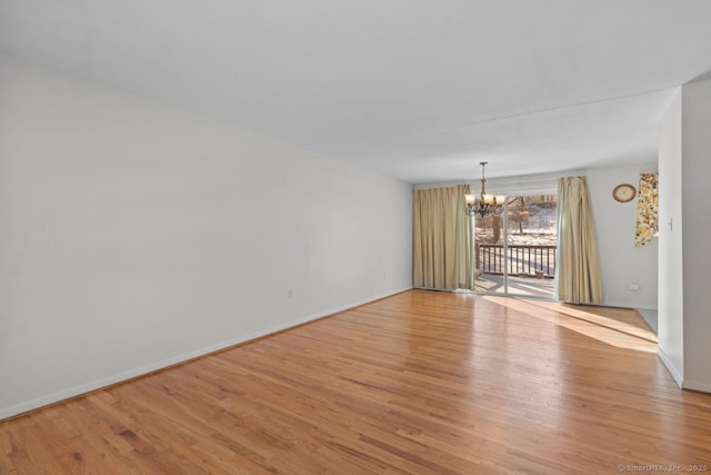 empty room with light hardwood / wood-style flooring and a notable chandelier