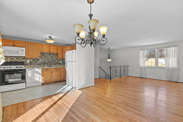 kitchen with pendant lighting, sink, white appliances, and light hardwood / wood-style flooring