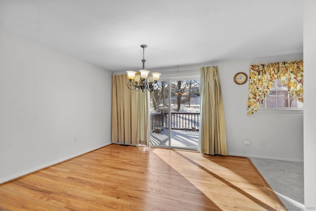 unfurnished dining area with a chandelier and hardwood / wood-style flooring