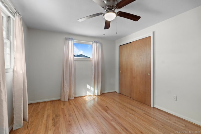 unfurnished bedroom featuring ceiling fan, a closet, and light wood-type flooring