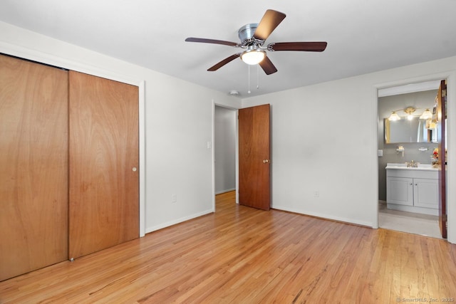 unfurnished bedroom featuring light hardwood / wood-style floors, ceiling fan, connected bathroom, a closet, and sink