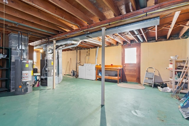 basement featuring water heater, heating unit, and independent washer and dryer