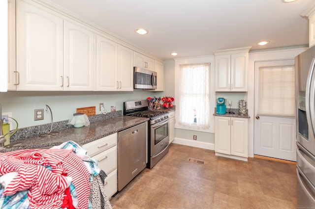 kitchen with white cabinetry, dark stone countertops, and appliances with stainless steel finishes