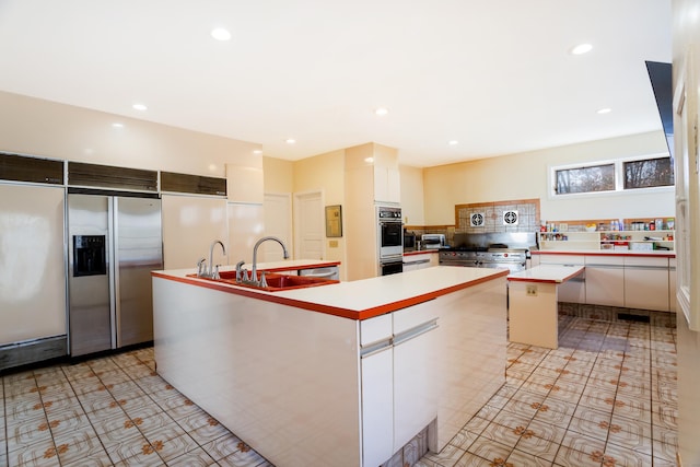 kitchen featuring premium appliances, a kitchen island, white cabinetry, sink, and light tile patterned floors