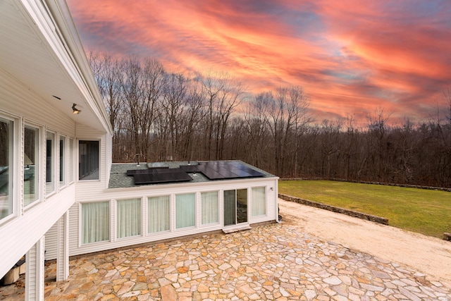 patio terrace at dusk featuring a yard