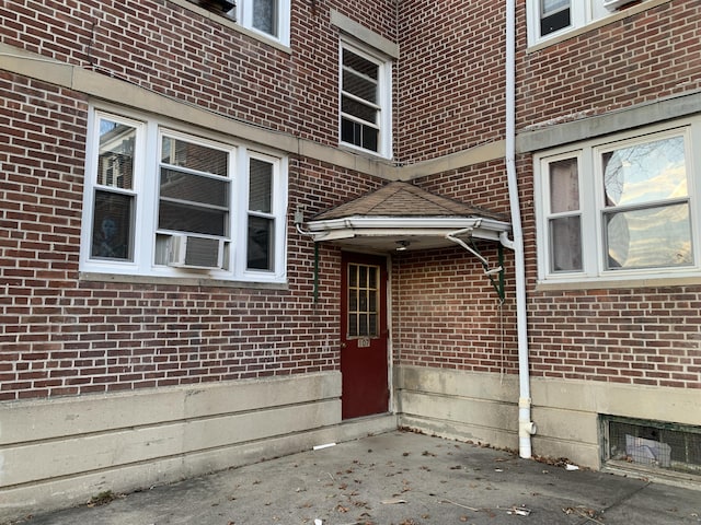 doorway to property with a patio, brick siding, and cooling unit