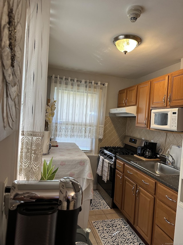 kitchen featuring tasteful backsplash, light tile patterned floors, sink, and stainless steel range with gas cooktop