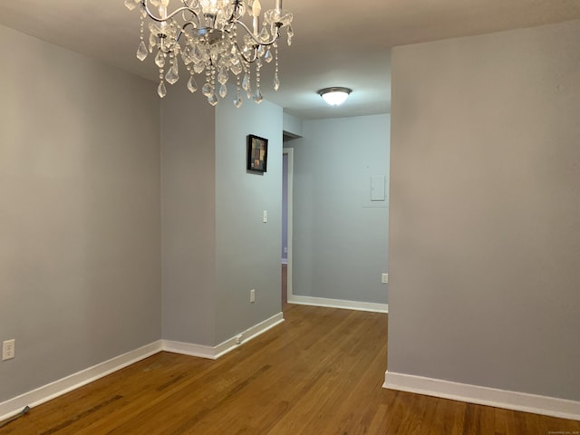 unfurnished room featuring hardwood / wood-style flooring and a chandelier