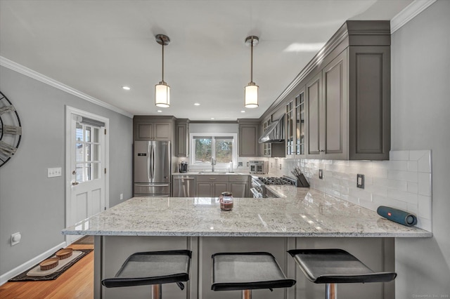 kitchen with appliances with stainless steel finishes, kitchen peninsula, hanging light fixtures, and a breakfast bar area