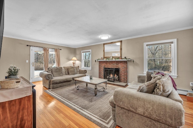 living room featuring crown molding, a fireplace, baseboard heating, and light wood-type flooring