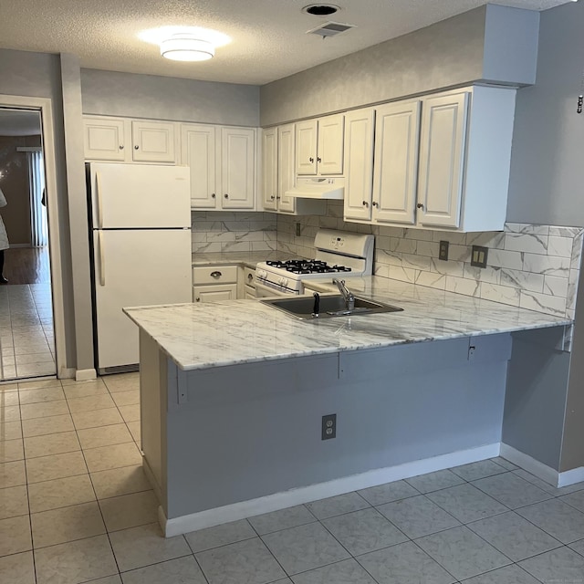 kitchen featuring light stone countertops, white appliances, white cabinetry, kitchen peninsula, and light tile patterned floors