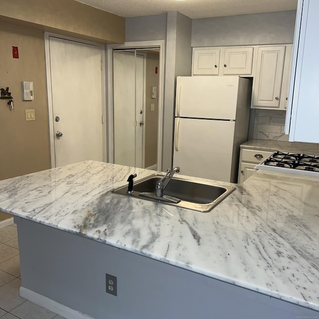 kitchen featuring white appliances, white cabinetry, sink, kitchen peninsula, and light tile patterned floors