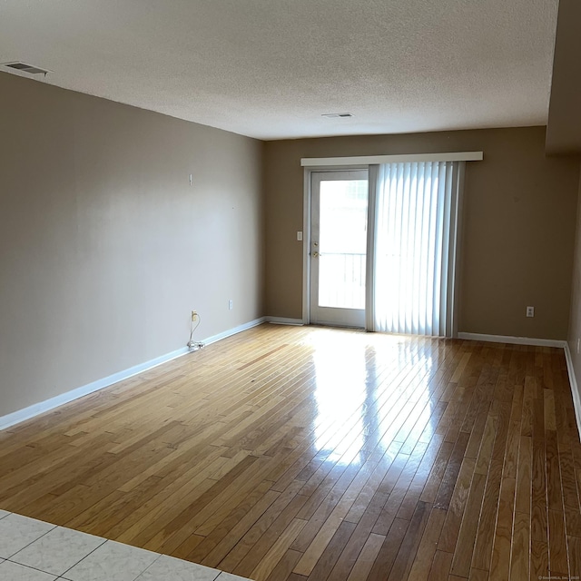 unfurnished room with a textured ceiling and light hardwood / wood-style floors