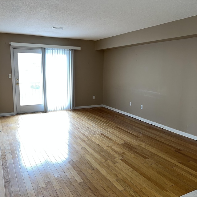 unfurnished room featuring light wood-type flooring and a textured ceiling