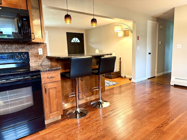 13 Lancer Dr, Enfield, CT 06082 - kitchen featuring black appliances, light wood-type flooring, a baseboard heating unit, and a breakfast bar area