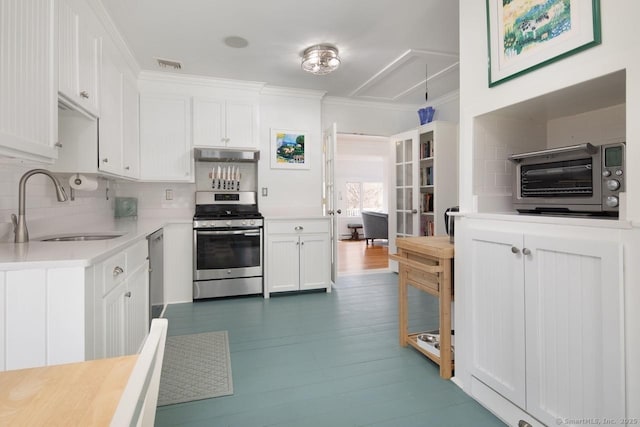 kitchen featuring white cabinetry, stainless steel appliances, tasteful backsplash, sink, and ornamental molding