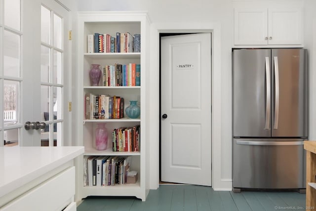 kitchen with white cabinets, stainless steel fridge, and a healthy amount of sunlight