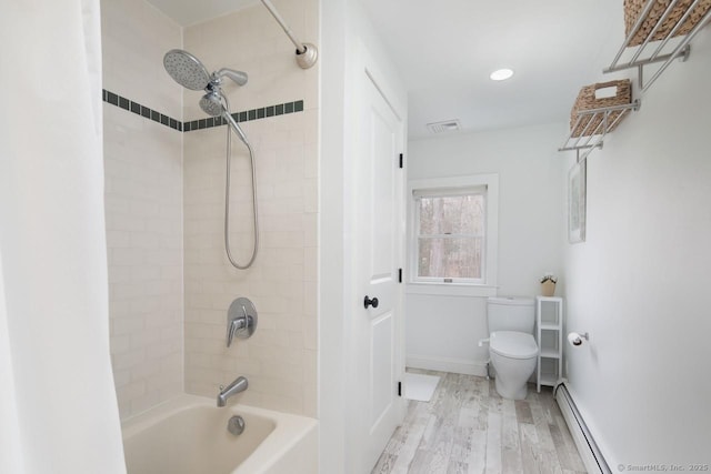 bathroom featuring toilet, tiled shower / bath, wood-type flooring, and a baseboard radiator