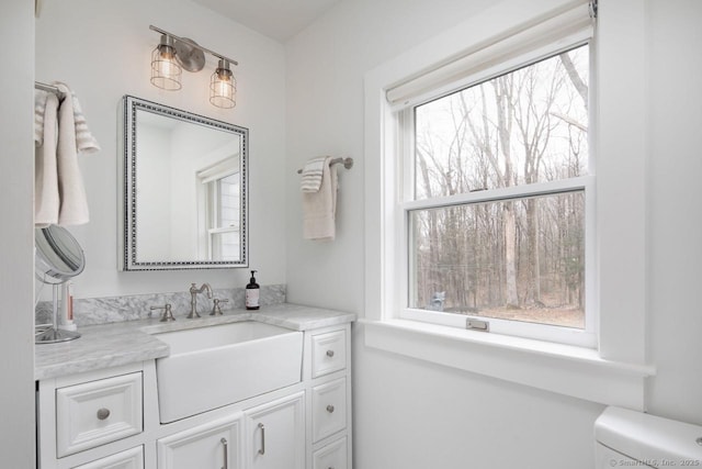 bathroom with toilet, vanity, and plenty of natural light