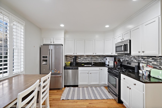 kitchen with appliances with stainless steel finishes, backsplash, white cabinetry, and sink