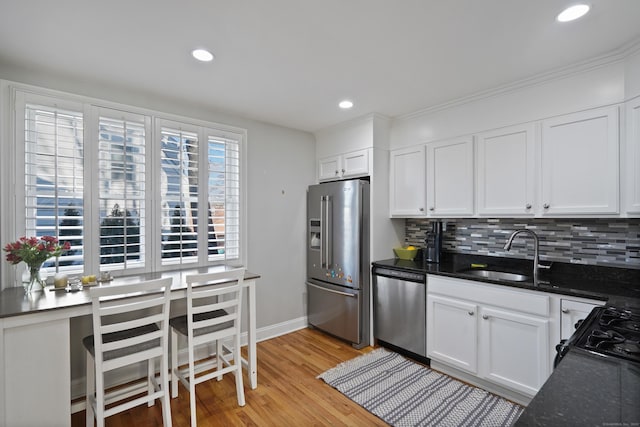 kitchen with stainless steel appliances, light hardwood / wood-style floors, white cabinets, and tasteful backsplash